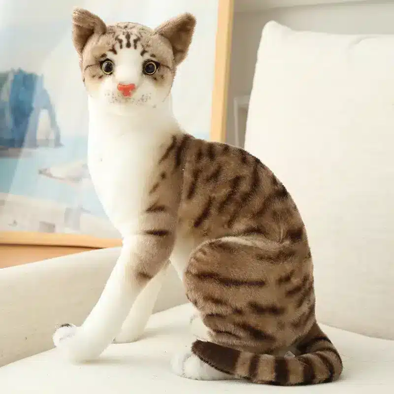 Peluche chat réaliste marron sur un canapé.