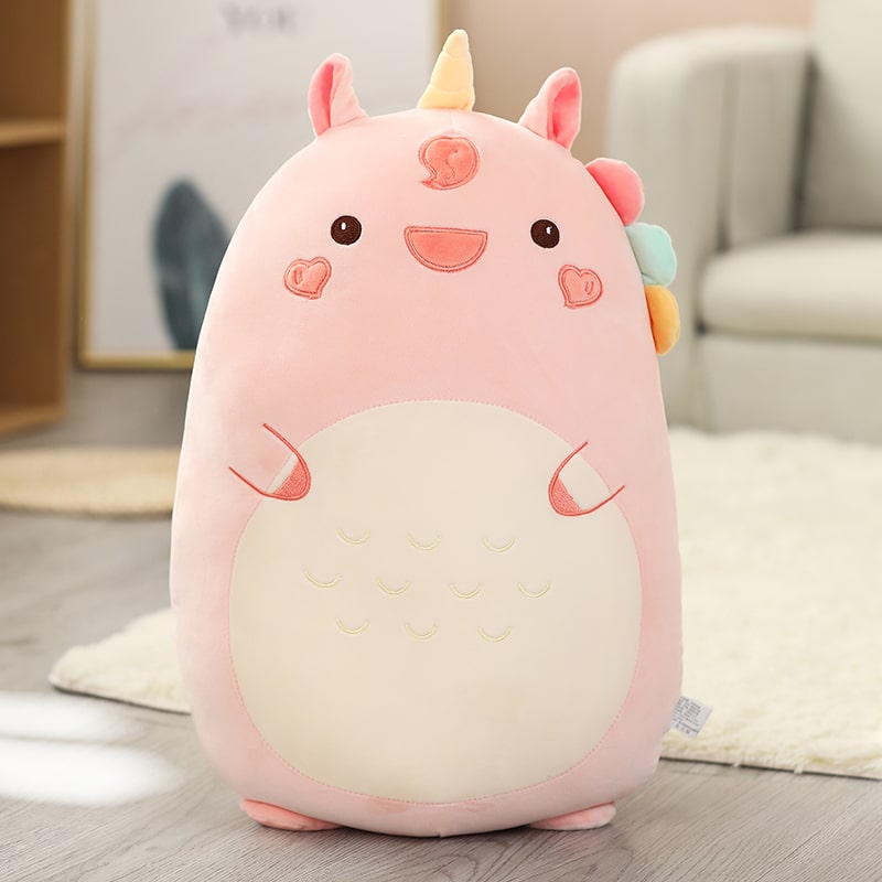 Une grande peluche licorne sur un sol en parquet.