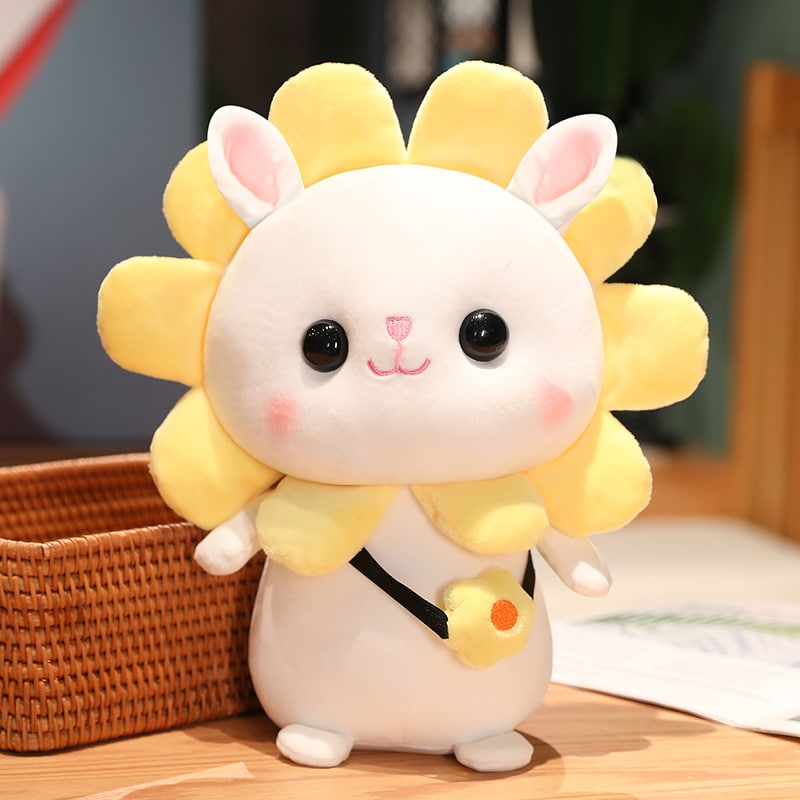 Une peluche lapin fleur jaune sur un plan de travail en bois.