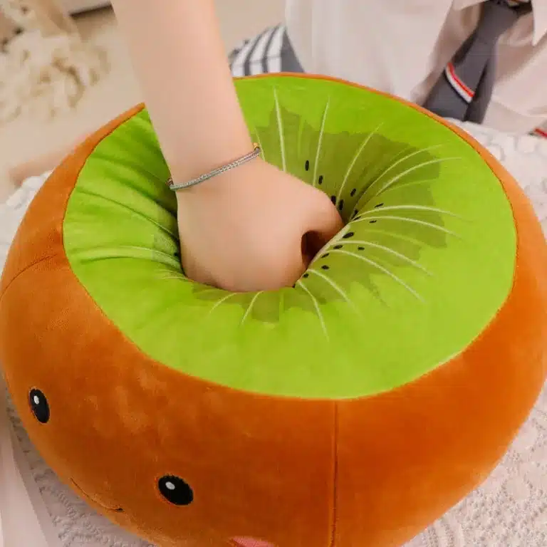 Peluche kiwi douce à motif de visage souriant touchée par une main