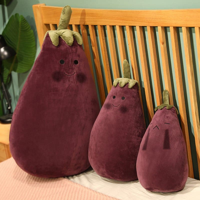 Peluche Légume aubergine assise sur une tapis rose