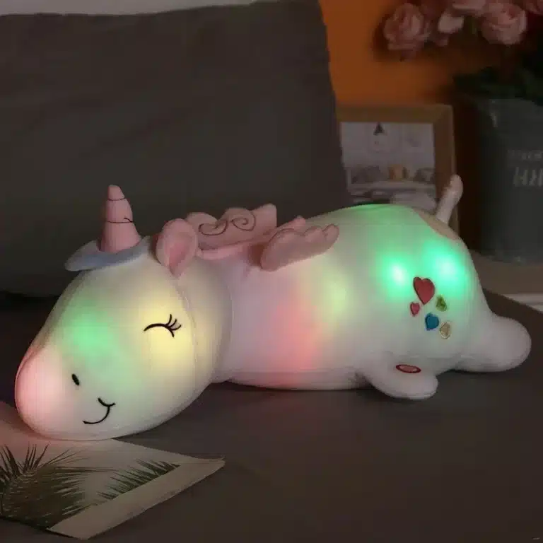 Peluche licorne avec lumière blanche charmante dans une chambre allongée sur un lit
