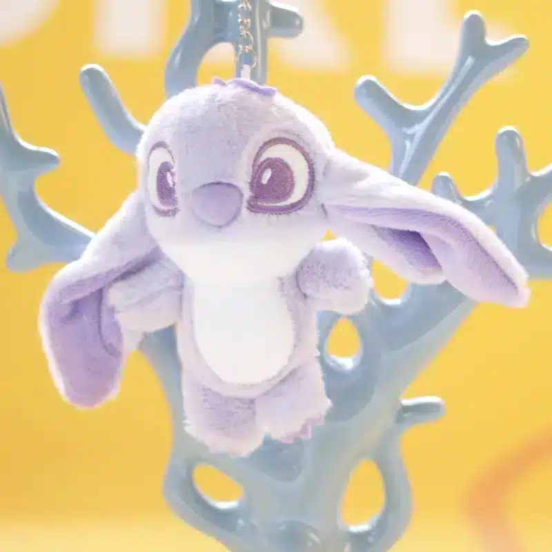 Porte-clés en peluche Stitch Disney en mauve accroché à une arbre en plastique.